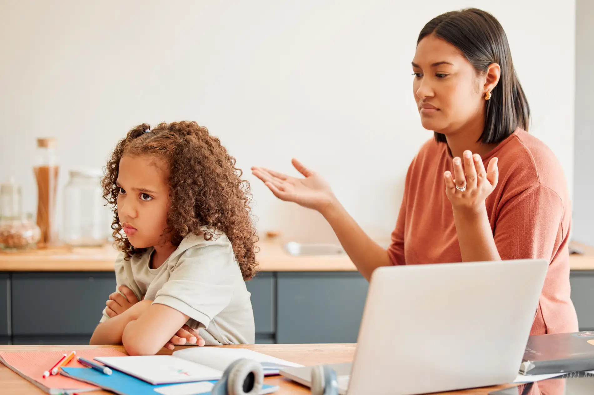Adult gesturing while a child sits with arms crossed